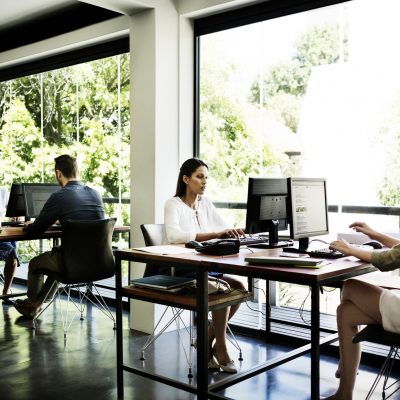 Business people working at desks by window in office